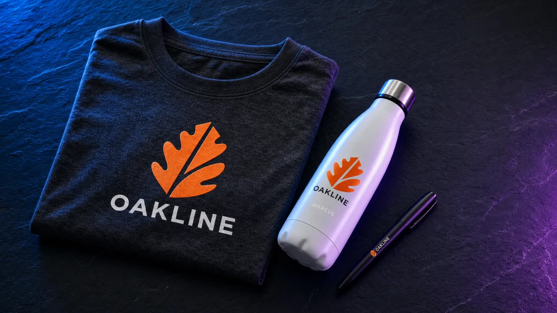 A folded shirt, a water bottle, and a pen laid out together, all carrying the same company logo
