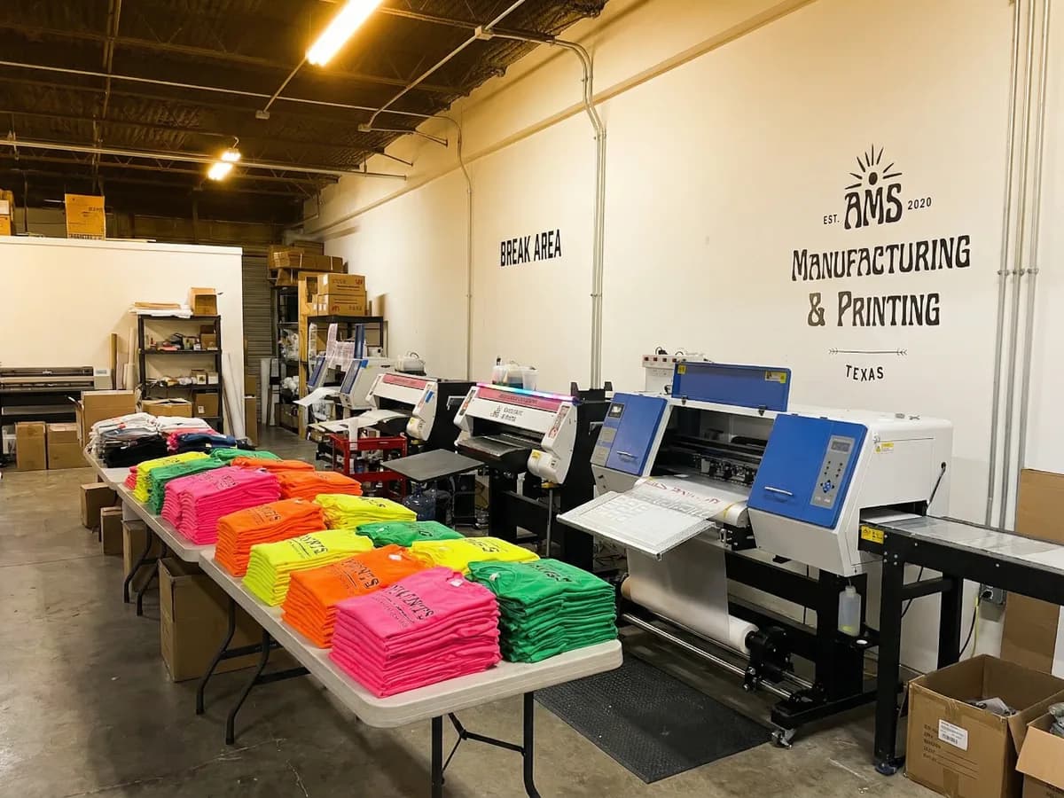 AMS Manufacturing and Printing production floor with DTF printers and colorful event shirt transfers