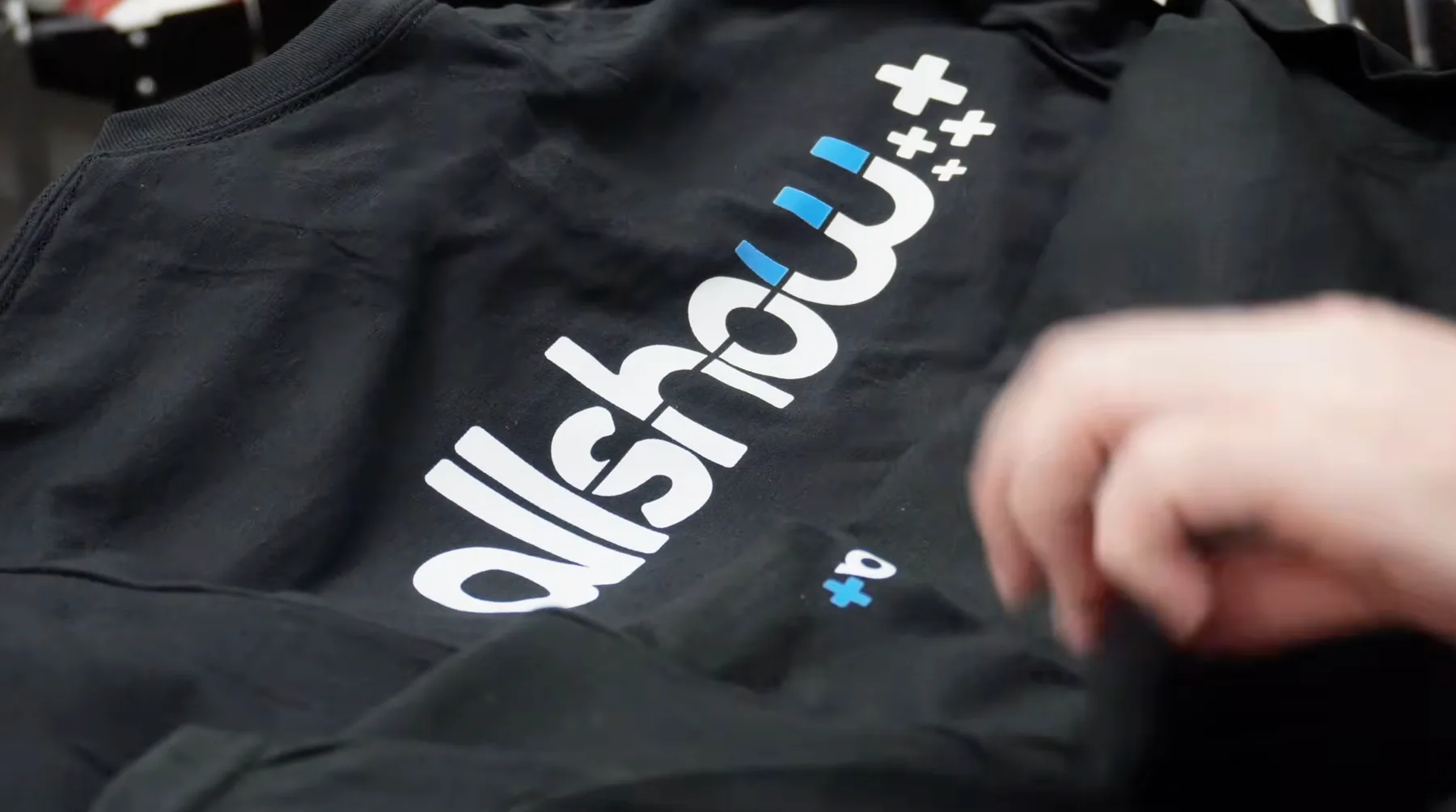 Black DryBlend shirt with a large DTF logo print being inspected on an AMS shop table