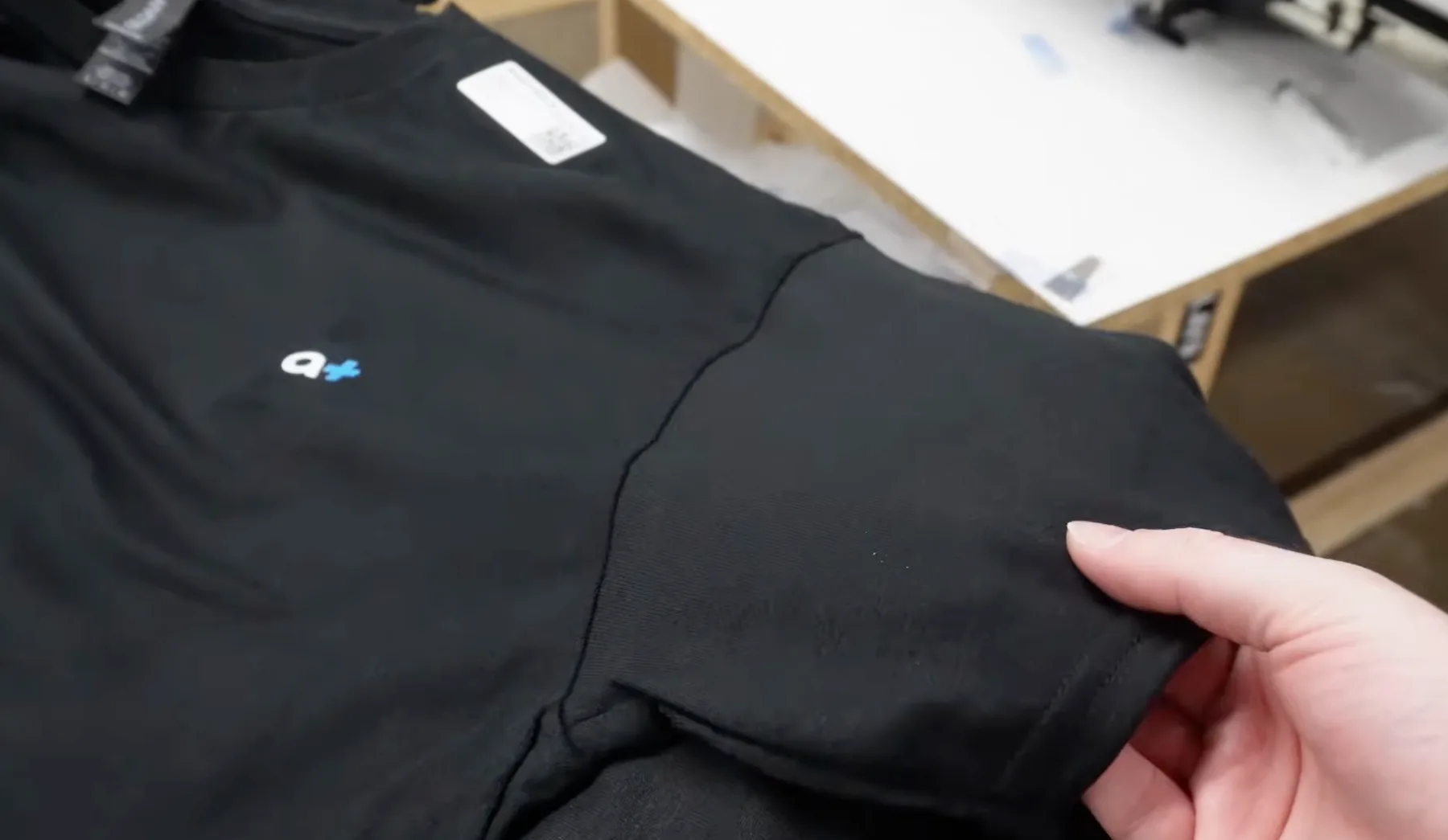 Hand lifting black Gildan DryBlend shirt fabric to show the lightweight everyday feel of the blank